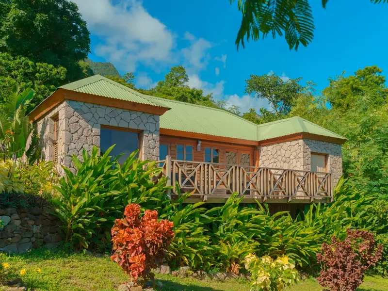 Bungalow des Hotel Jungle Bay auf Dominica, eingebettet in einen tropischen Garten unter blauem Karibikhimmel.