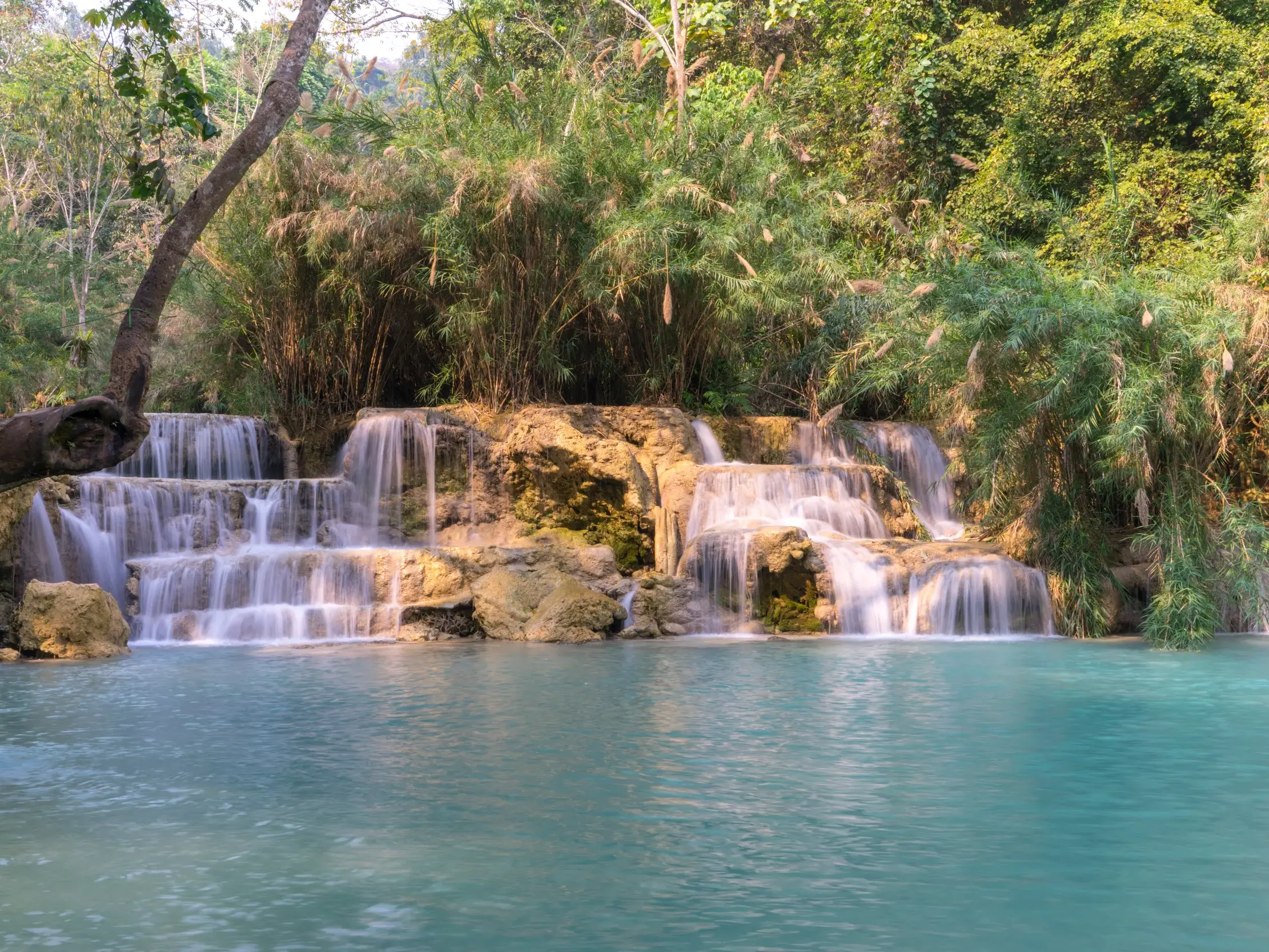 Der Kuang Si Wasserfall bei Luang Prabang in Laos mit seinen Kaskaden, die in ein türkises Becken inmitten des Dschungels fließen.