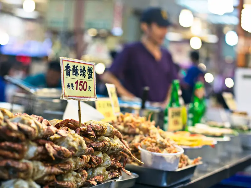 Traditioneller Marktstand mit frittierten Krabben und Meeresfrüchten auf einem lebhaften Nachtmarkt in Taiwan