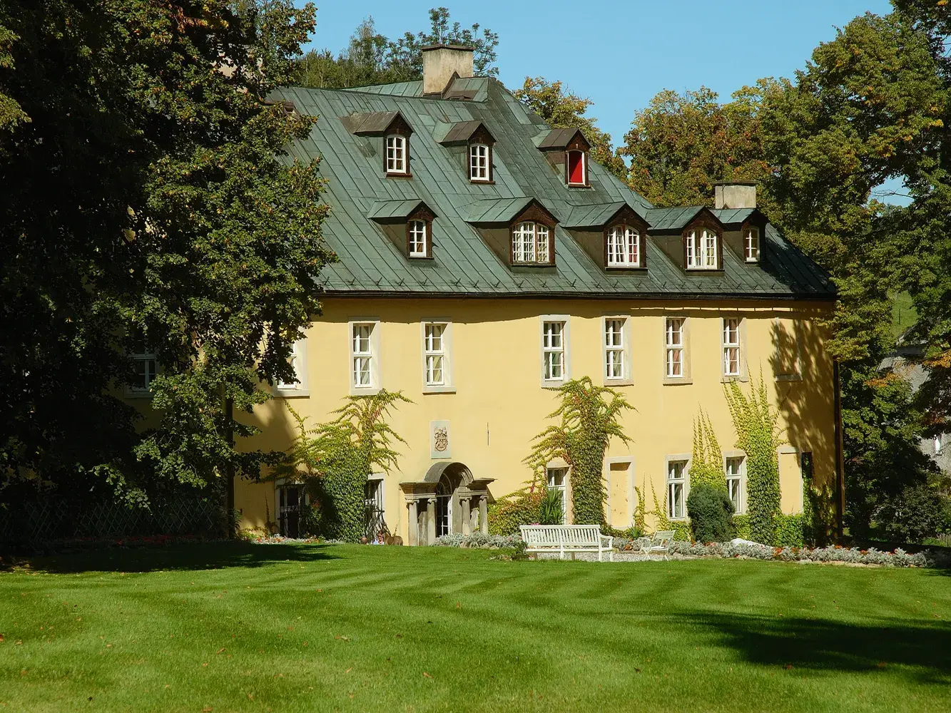 Historische Außenansicht des Hotel Schloss Stonsdorf in Staniszów mit gelber Fassade und gepflegtem Schlosspark.