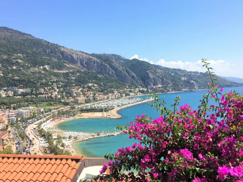 Belohnende Aussicht auf einer Wanderung über die Bucht von Menton, mit blühender Bougainvillea an der Côte d'Azur.