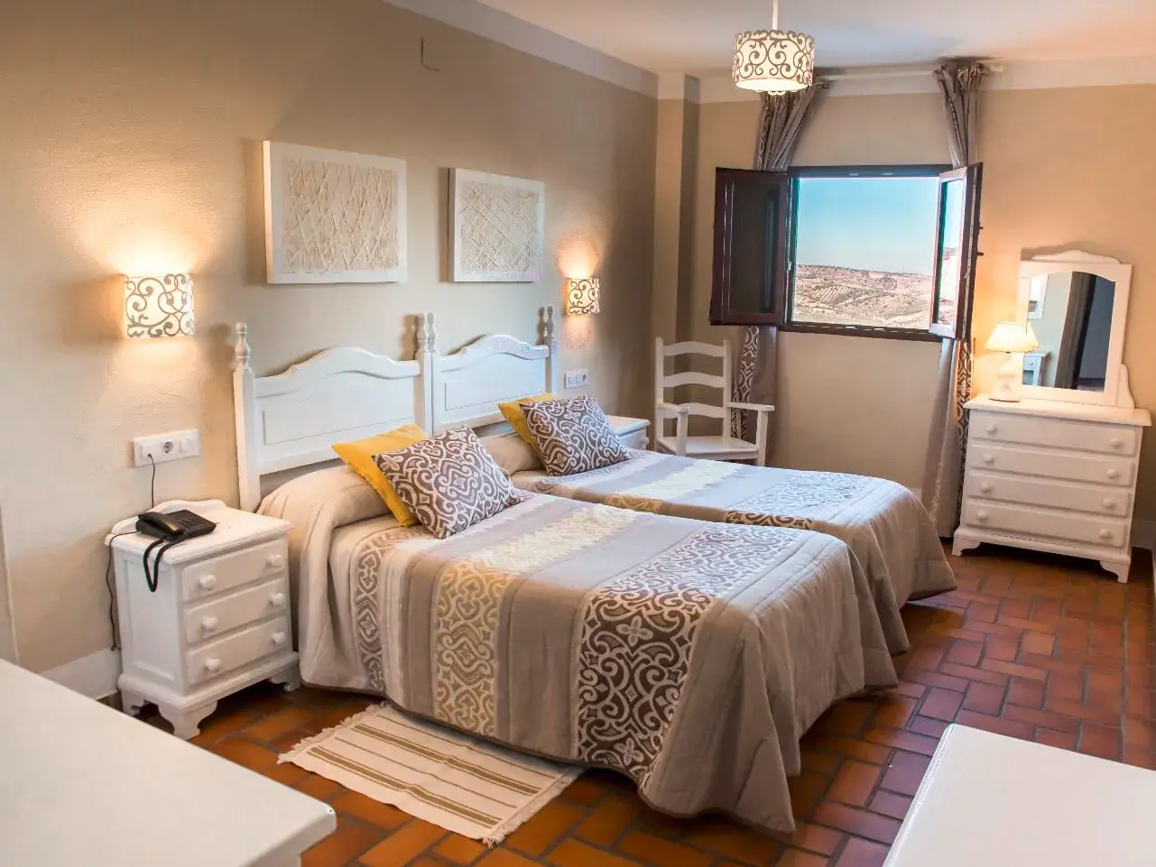 Rustikales Zweibettzimmer im Landhotel Zuhayra in Zuheros mit weißem Mobiliar und Blick auf die weite Landschaft mit Olivenbäumen.