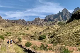 Zwei Trekking-Reisende wandern auf einem Hirtenpfad durch die zerklüftete Vulkanlandschaft der Kapverden-Insel Santo Antão.