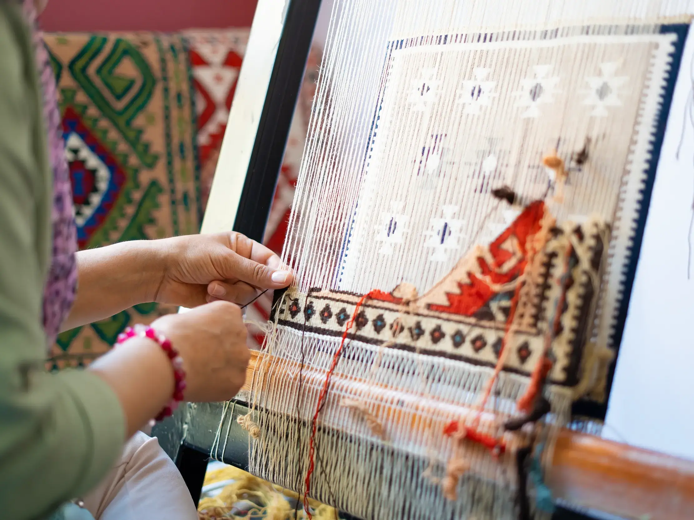 Eine Weberin fertigt in einem Teppichzentrum kunstvoll einen anatolischen Teppich an einem traditionellen Webstuhl.