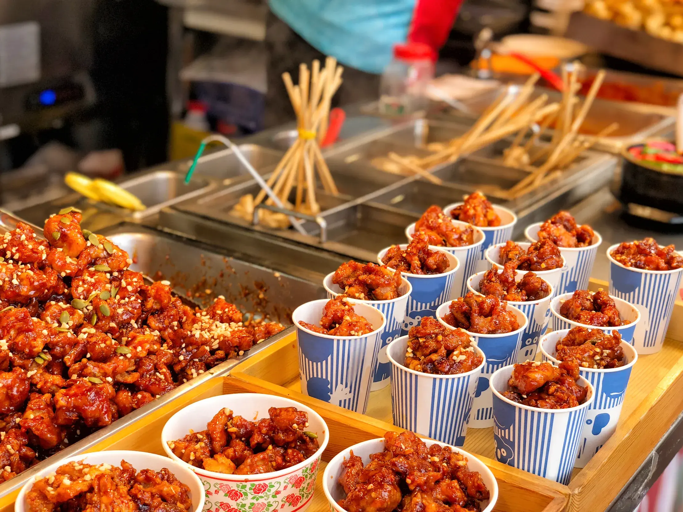 Portionen von süß-scharfem, koreanischem Brathähnchen mit Sesam auf einem Streetfood-Markt