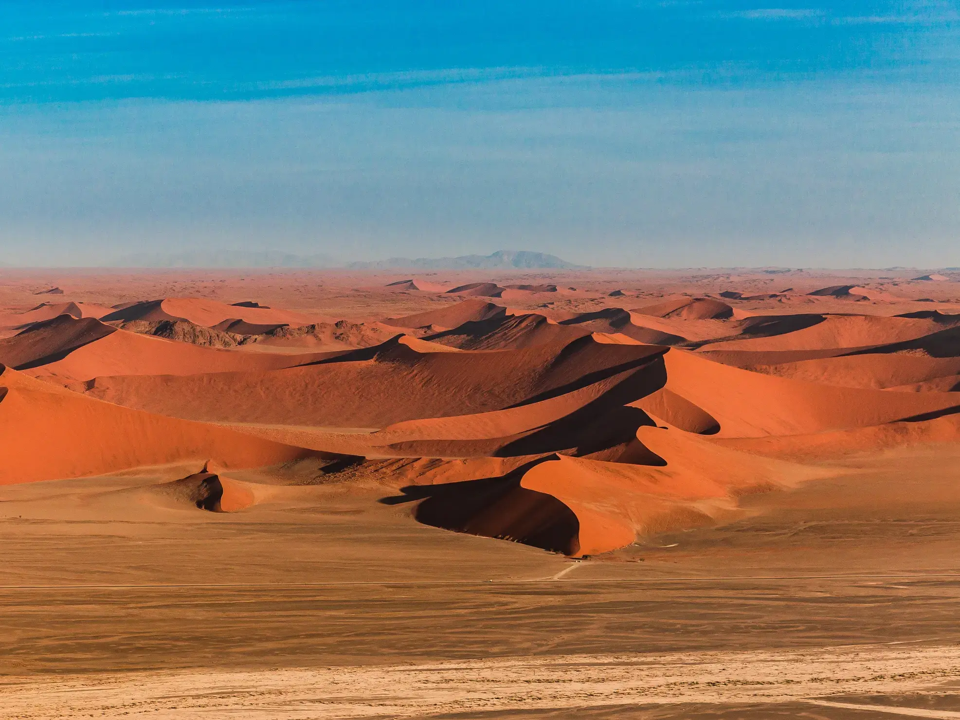 Weitblick über das endlose, rote Dünenmeer von Sossusvlei im Namib-Naukluft-Park unter einem strahlend blauen Himmel.