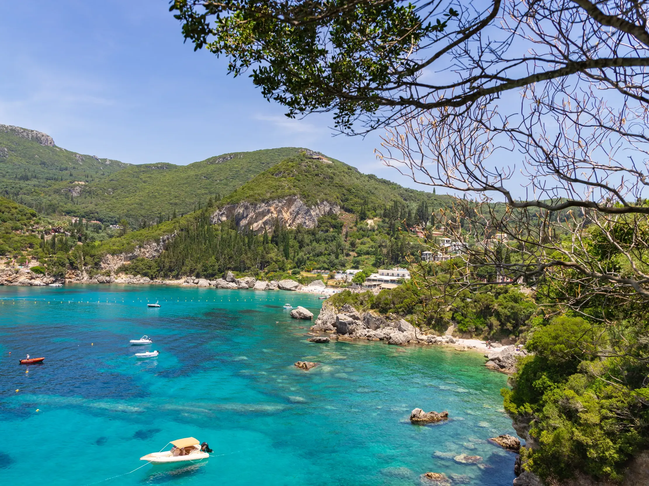 Ausblick während einer Wanderung auf Korfu auf eine malerische Bucht bei Liapades mit türkisem Meer und Booten.