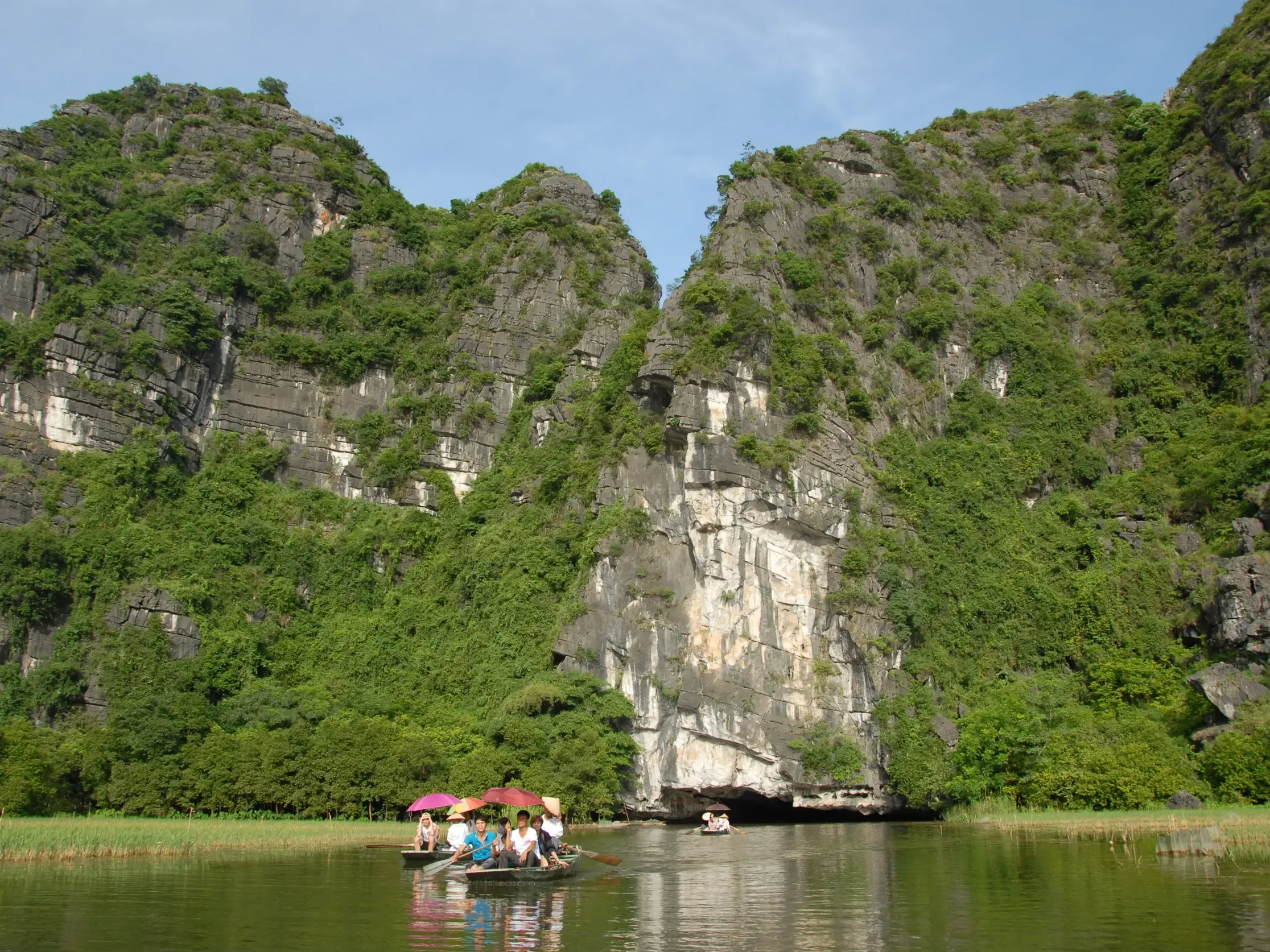 Reisegruppe erkundet auf einer Bootsfahrt die beeindruckenden Karstfelsen der trockenen Halong Bucht bei Tam Coc in Vietnam.