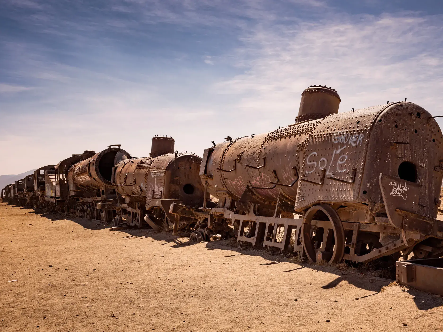 Rostige Dampflokomotiven und Waggons auf dem Eisenbahnfriedhof Cementerio de Trenes in der Wüste bei Uyuni in Bolivien.