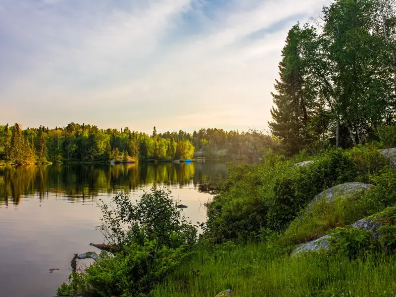 Abendstimmung auf einer Radreise in der Thousand-Islands-Region in Kanada, wo sich dichte Wälder im stillen See spiegeln.
