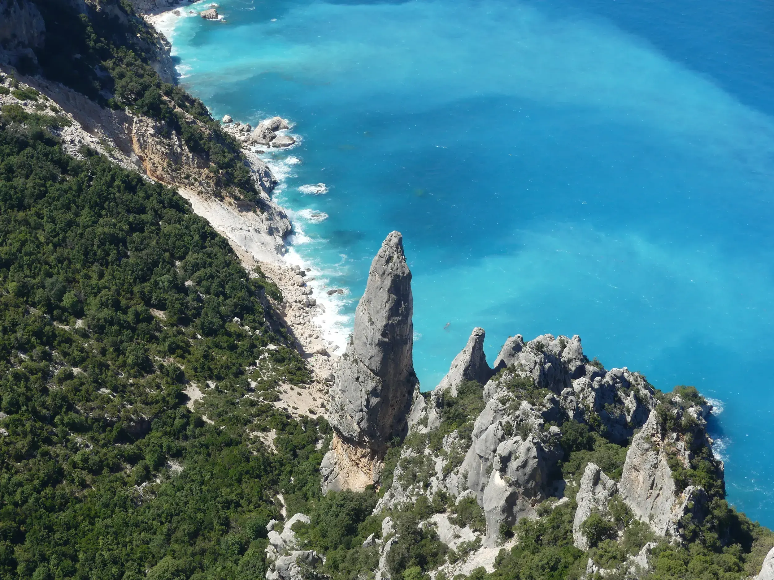Blick von der Punta Salinas im Supramonte von Baunei auf eine Felsnadel an der Steilküste des türkisblauen Golf von Orosei.