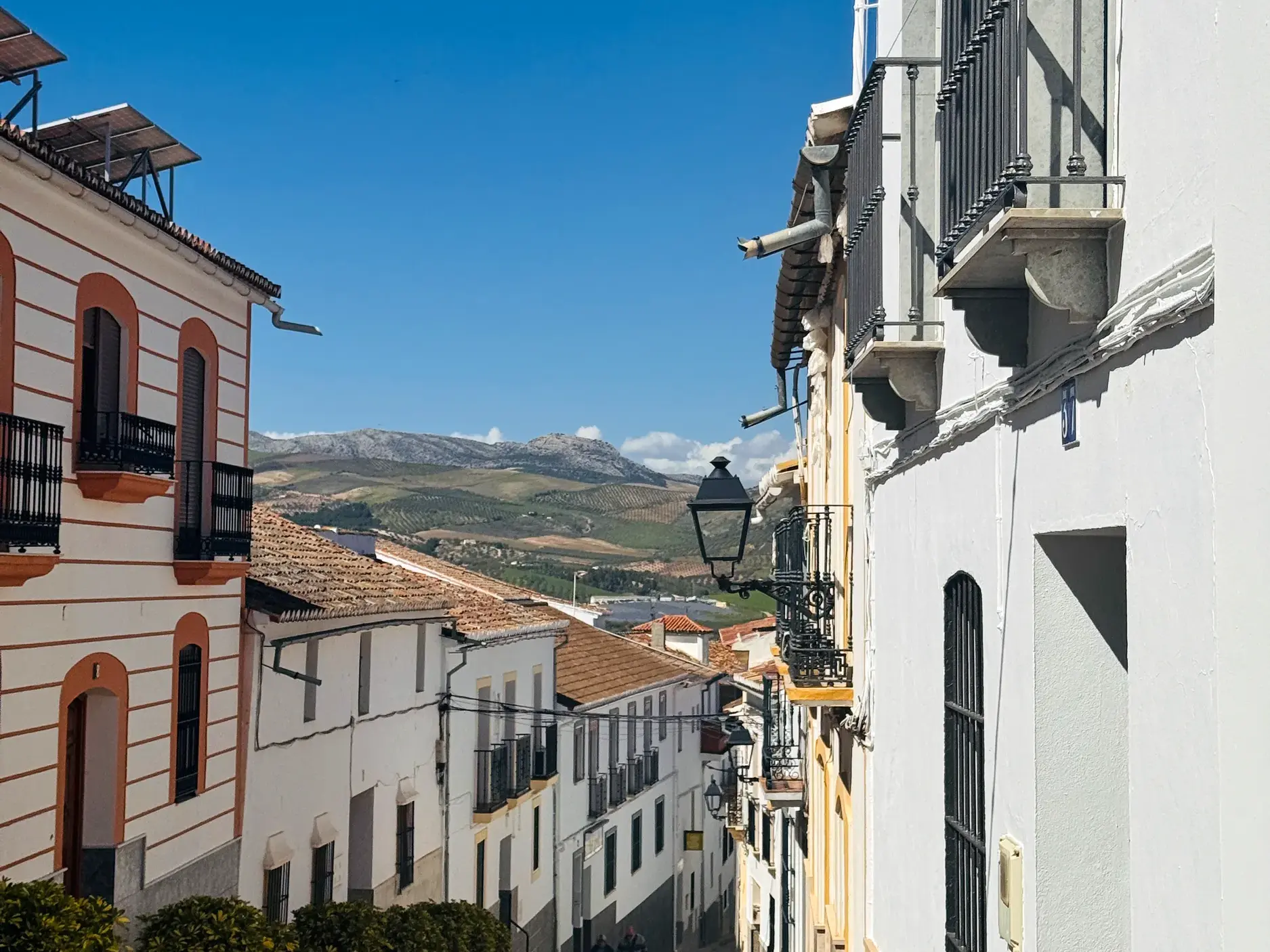 Enge Gasse in einem Dorf in Andalusien mit Blick auf die hügelige Landschaft an einem sonnigen Tag.