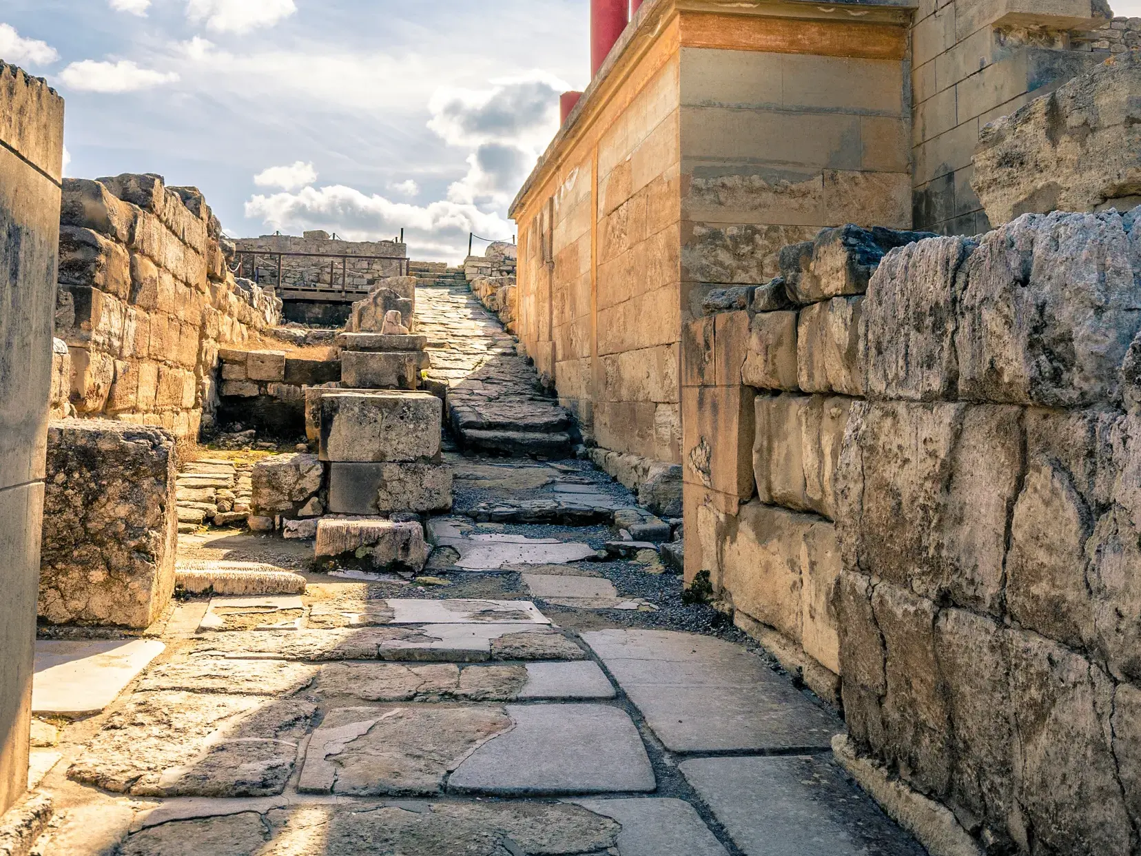 Ein alter Steinweg führt durch die sonnigen Ruinen des minoischen Palastes von Knossos auf Kreta bergauf