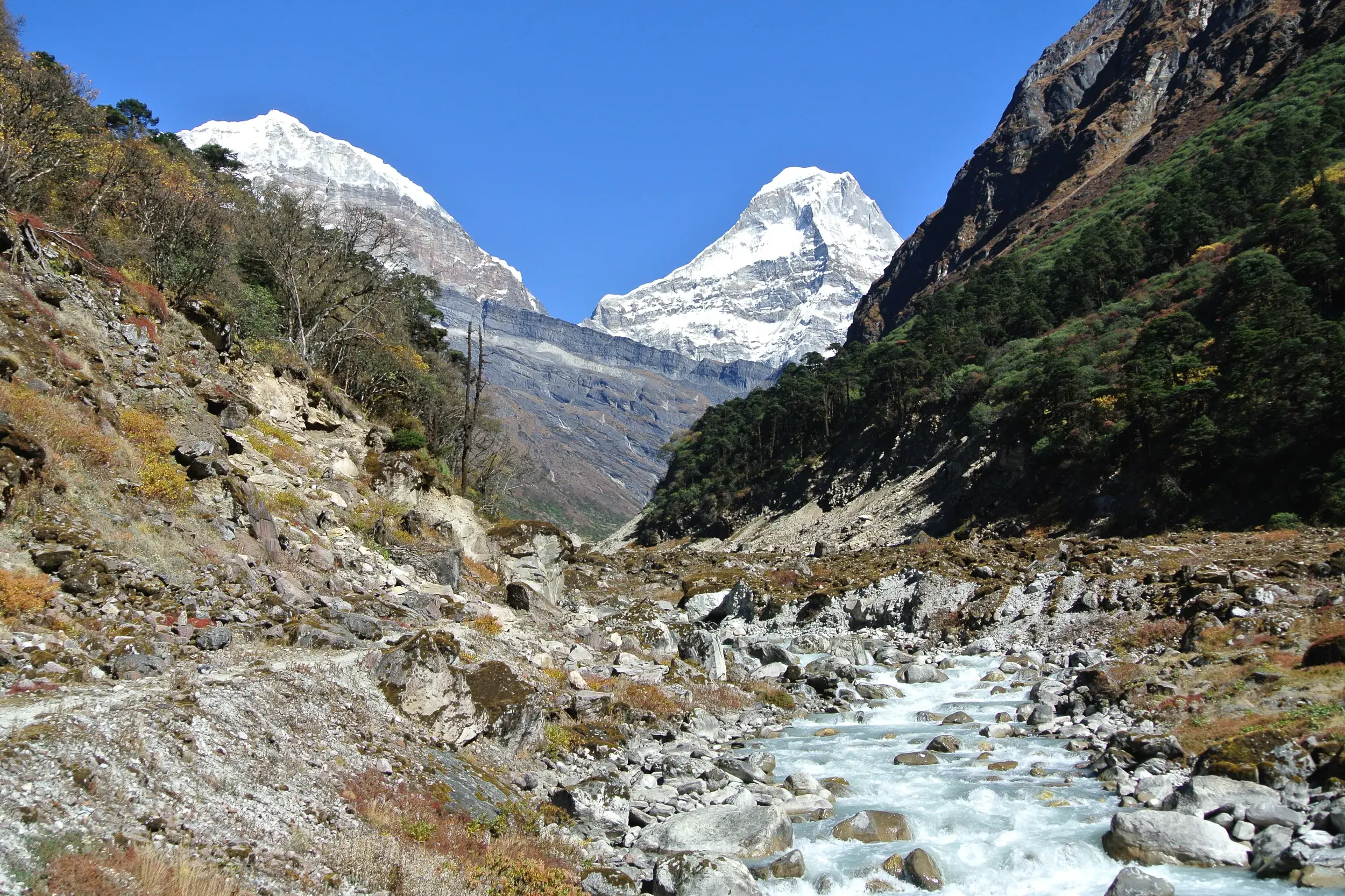 Wanderweg entlang des Flusses Hinku Khola im Hinku-Tal mit Blick auf schneebedeckte Gipfel im nepalesischen Himalaya.