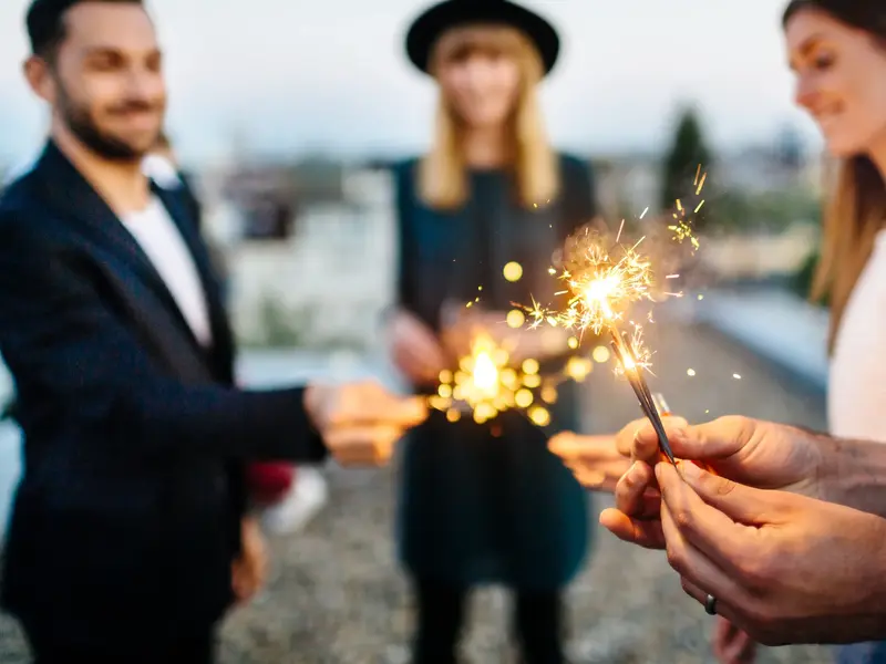 Eine kleine Gruppe Alleinreisender feiert mit funkelnden Wunderkerzen auf einer Singlereise gemeinsam Silvester .