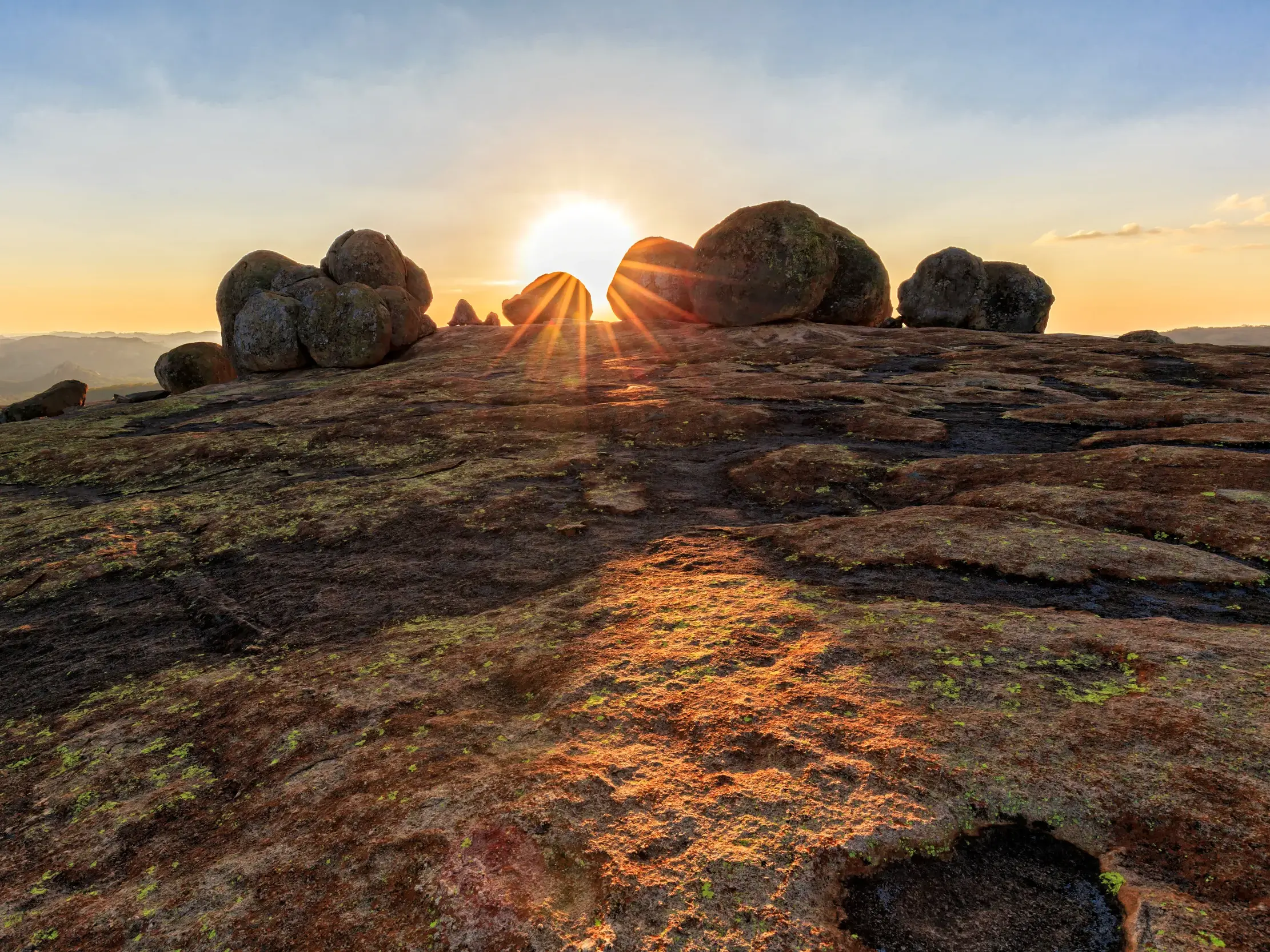 Die aufgehende Sonne scheint über die einzigartigen Granitfelsen am Aussichtspunkt "World's View" im Matobo-Nationalpark.