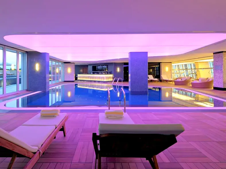 Eleganter Innenpool des Hotel Radisson in Batumi, Georgien mit stimmungsvoller violetter Beleuchtung und einer modernen Poolbar.