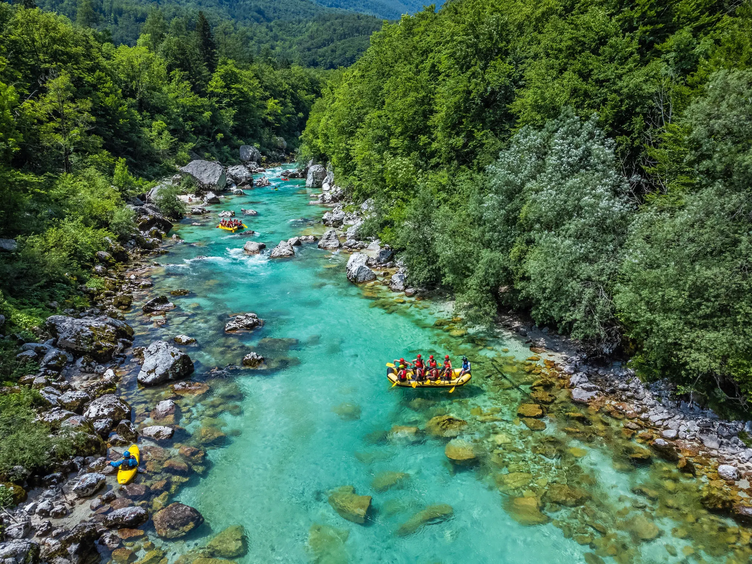 Luftaufnahme einer jungen Reisegruppe beim Rafting auf der smaragdgrünen Soca in den Julischen Alpen in Slowenien.
