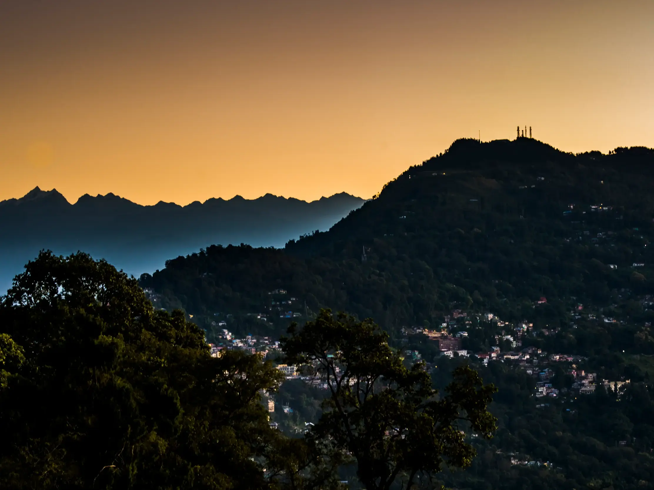 Die Silhouette des Kangchendzönga-Massivs im Himalaya bei Sonnenuntergang über den bewaldeten Hügeln von Kalimpong