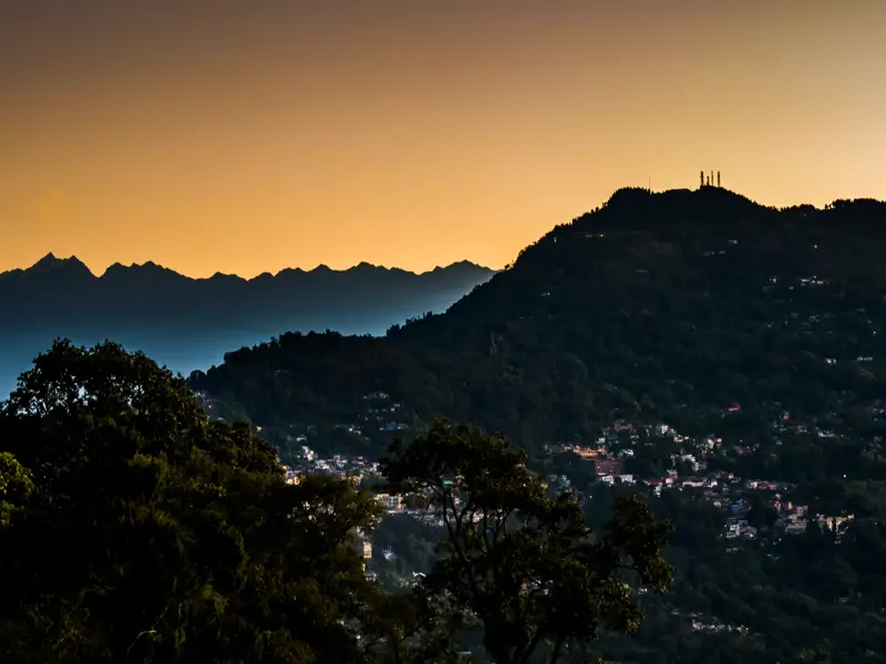 Die Silhouette des Kangchendzönga-Massivs im Himalaya bei Sonnenuntergang über den bewaldeten Hügeln von Kalimpong