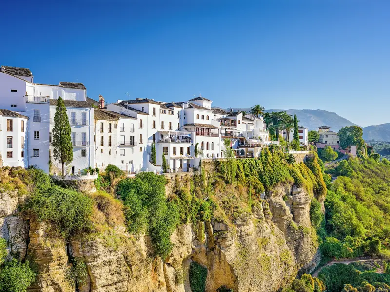 Spektakuläre Aussicht auf die weißen Häuser von Ronda, die auf einem von Grün bewachsenen Felsplateau in Andalusien thronen.