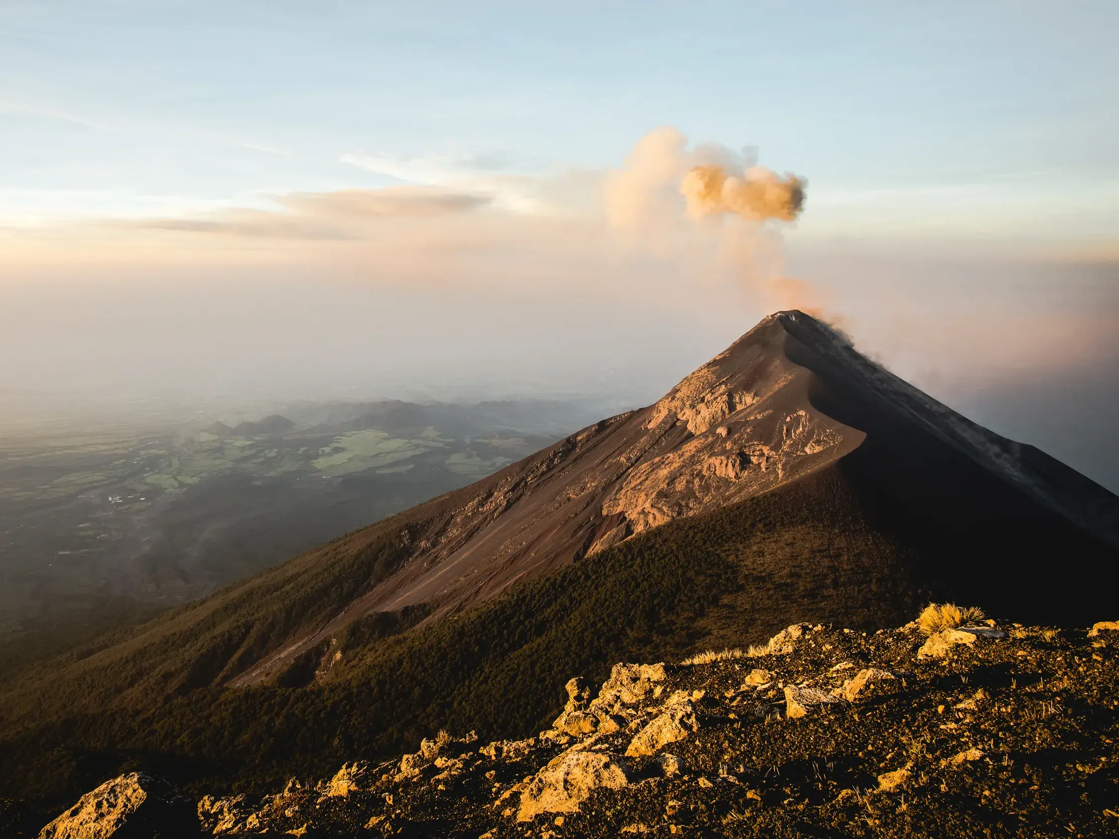 Der aktive Vulkan Fuego stößt bei Sonnenaufgang eine Rauchwolke aus, gesehen vom Gipfel des Acatenango während einer Trekkingreise.
