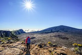 Eine Person beim Trekking am Rande der riesigen Caldera des aktiven Vulkans Piton de la Fournaise auf La Réunion.