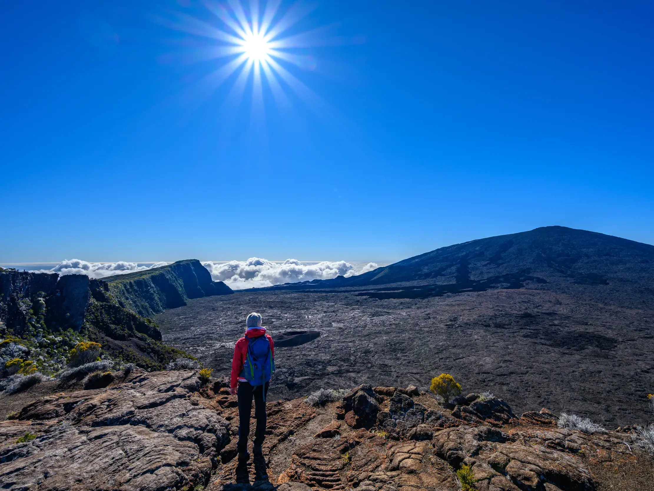 Wanderer bei einer Trekking-Tour auf La Réunion blickt auf die riesige Caldera des aktiven Vulkans Piton de la Fournaise.
