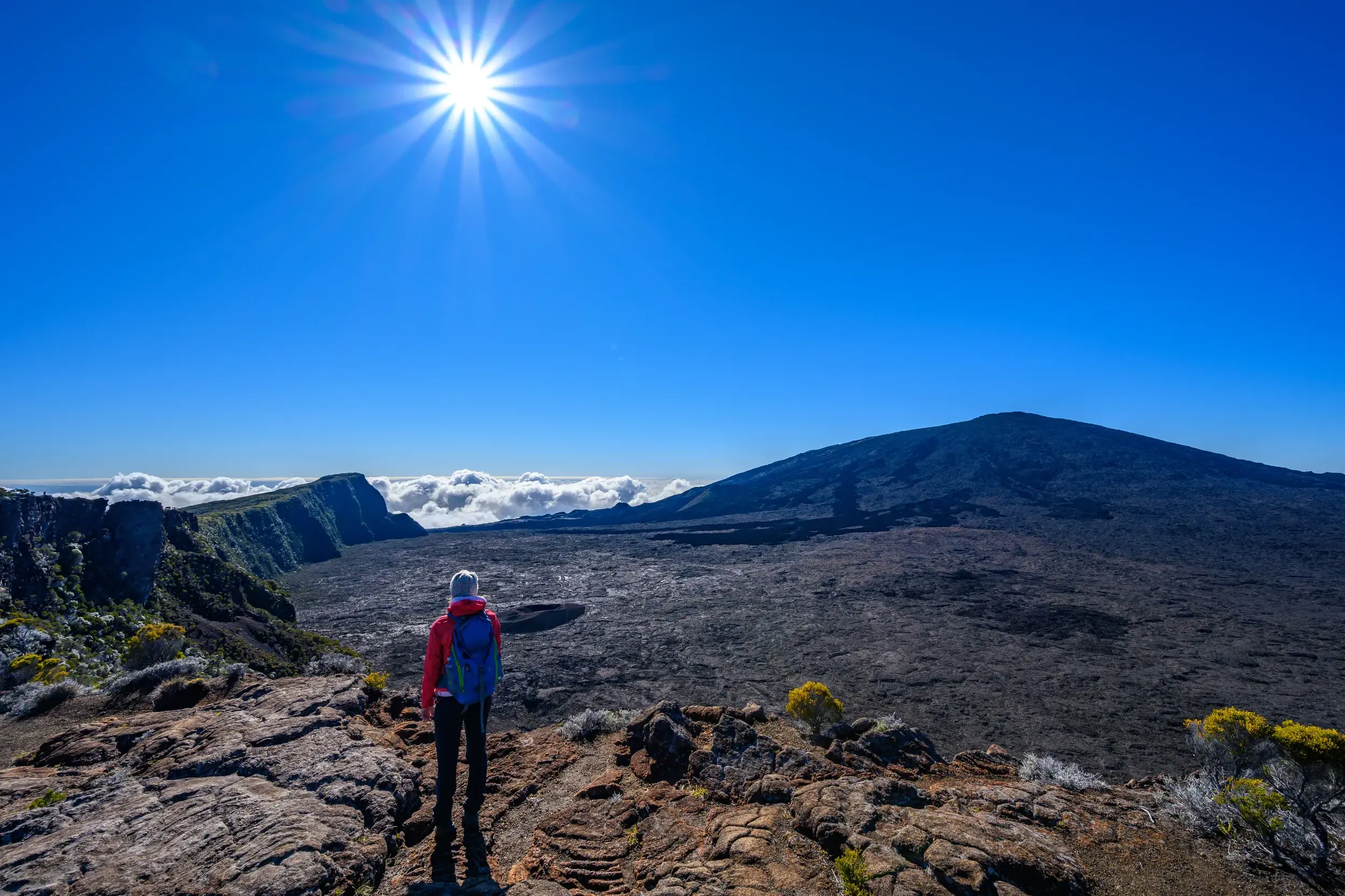 Wanderer bei einer Trekking-Tour auf La Réunion blickt auf die riesige Caldera des aktiven Vulkans Piton de la Fournaise.
