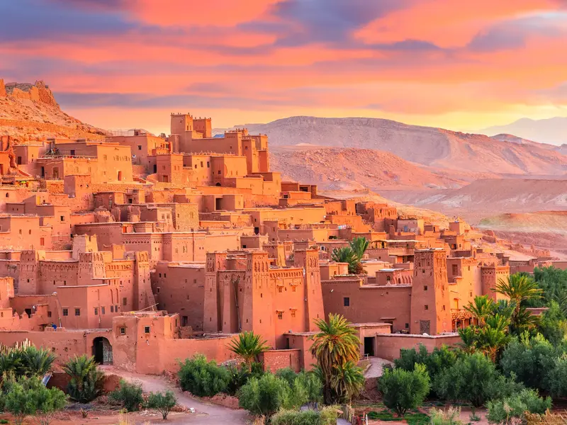 Die historische Berberburg Ait Benhaddou mit traditioneller Lehmarchitektur und Oasengrün im warmen Abendlicht