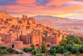 Die historische Berberburg Ait Benhaddou mit traditioneller Lehmarchitektur und Oasengrün im warmen Abendlicht