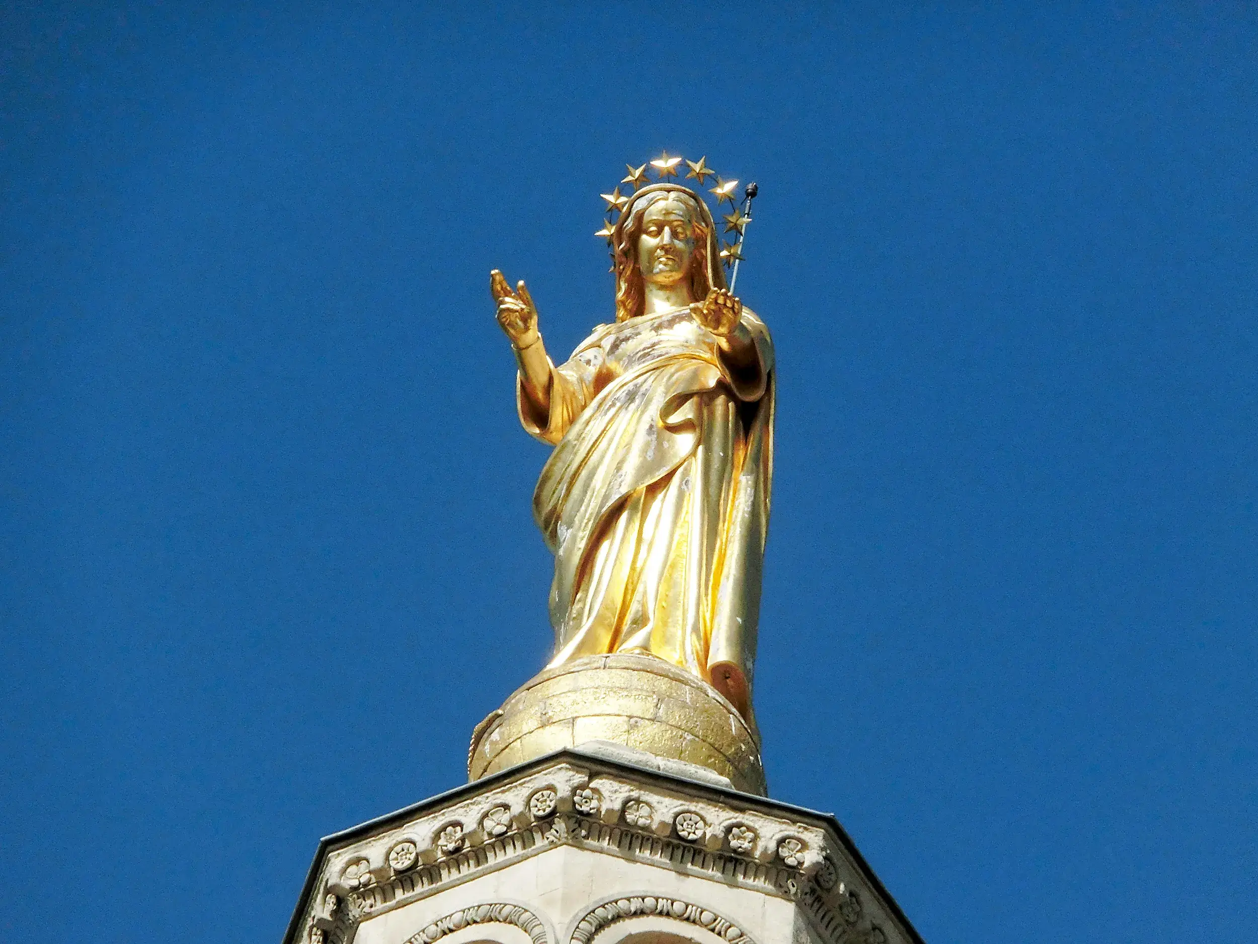 Die vergoldete Marienstatue auf der Kathedrale von Avignon unter strahlend blauem Himmel.