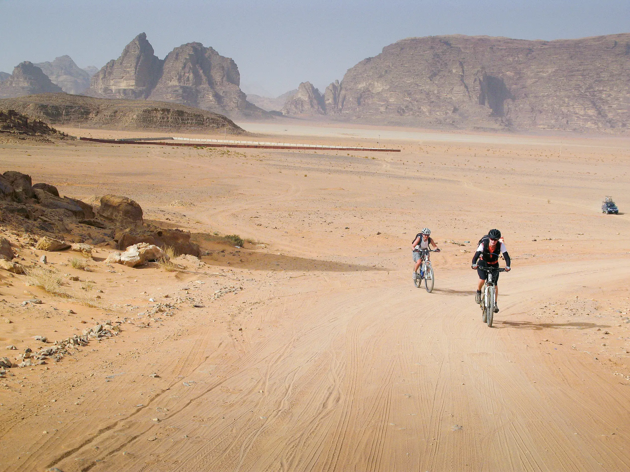Zwei Mountainbiker auf einer geführten Radreise auf einem sandigen Offroad-Pfad durch die Wüste von Wadi Rum in Jordanien.
