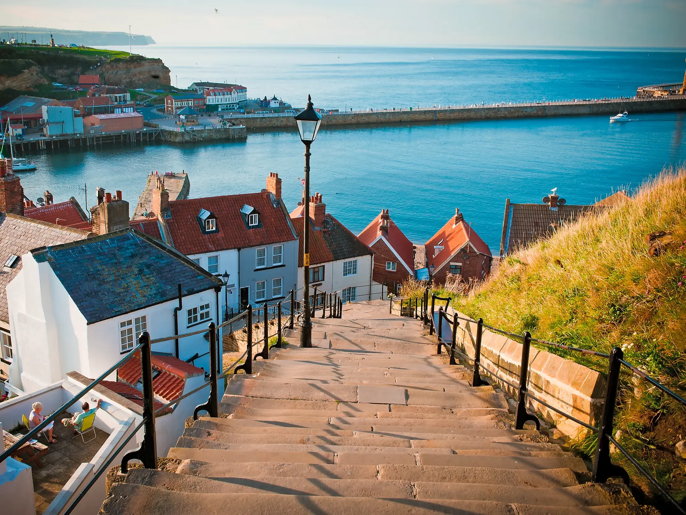 Blick über die steilen 199 Stufen hinab auf die Dächer und den Hafen des Küstenstädtchens Whitby in Nordengland.
