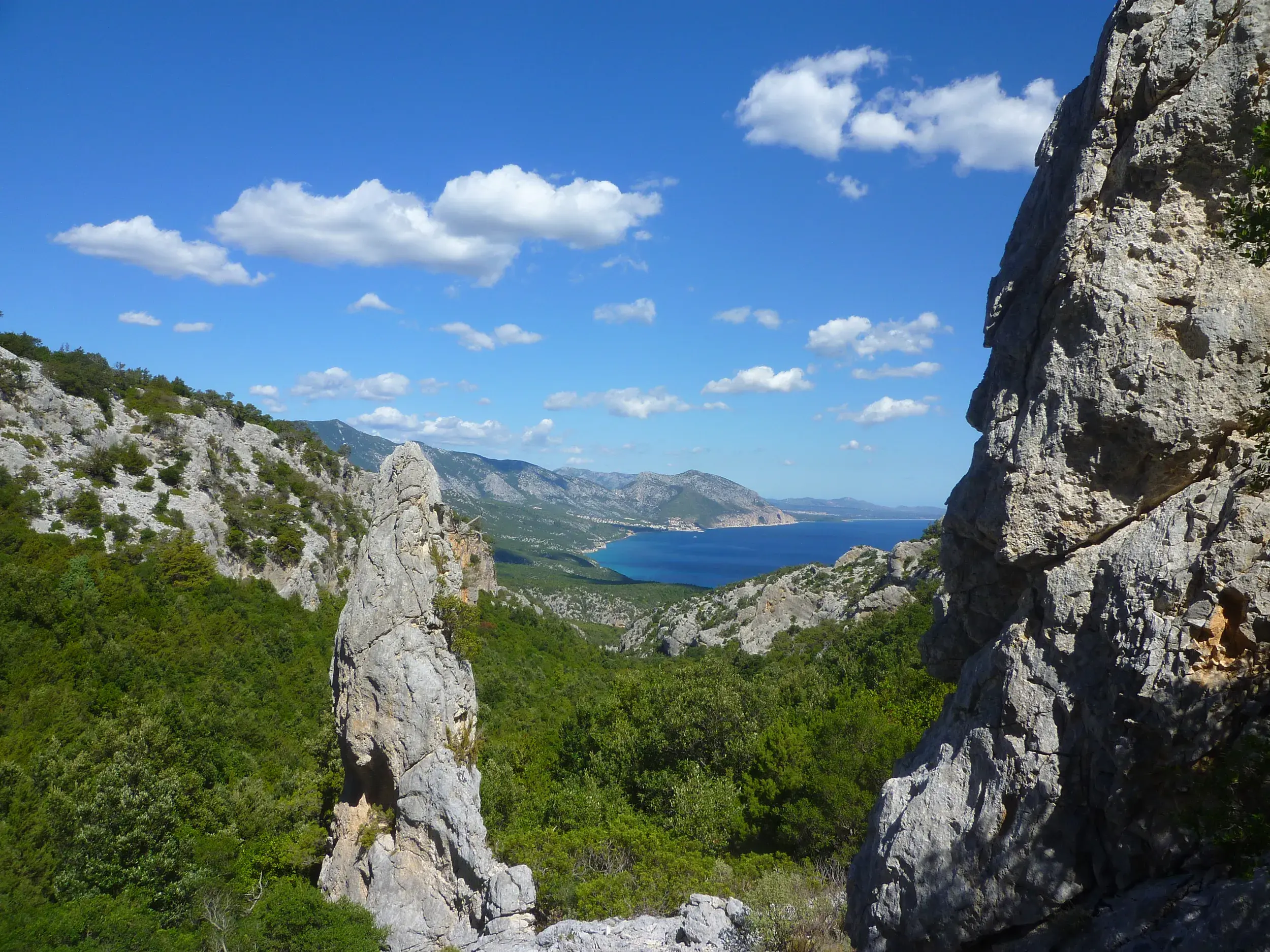 Panoramablick beim Wandern von der Punta Salinas auf die Felsenküste und das blaue Meer am Golf von Orosei auf Sardinien.