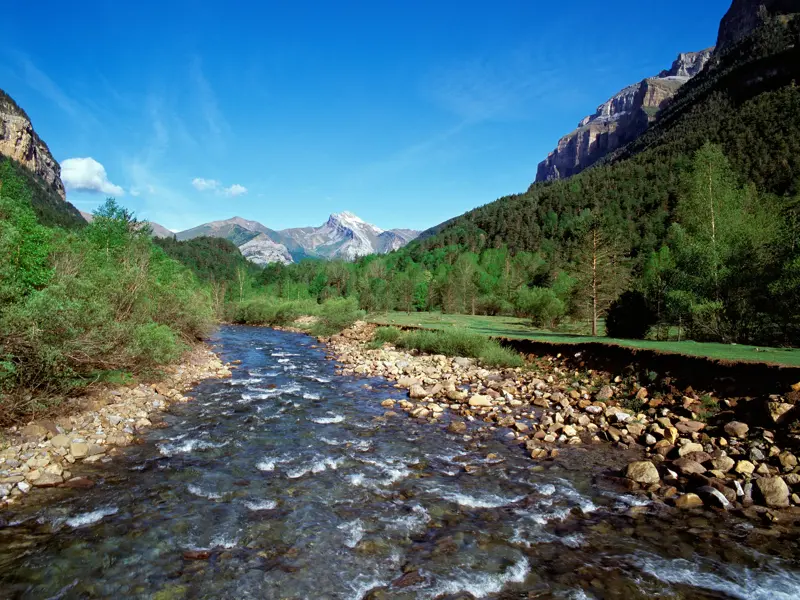 Klarer Bergfluss Río Arazas im grünen Tal des Ordesa-Nationalparks, ein Höhepunkt der Wanderreise durch die Pyrenäen.