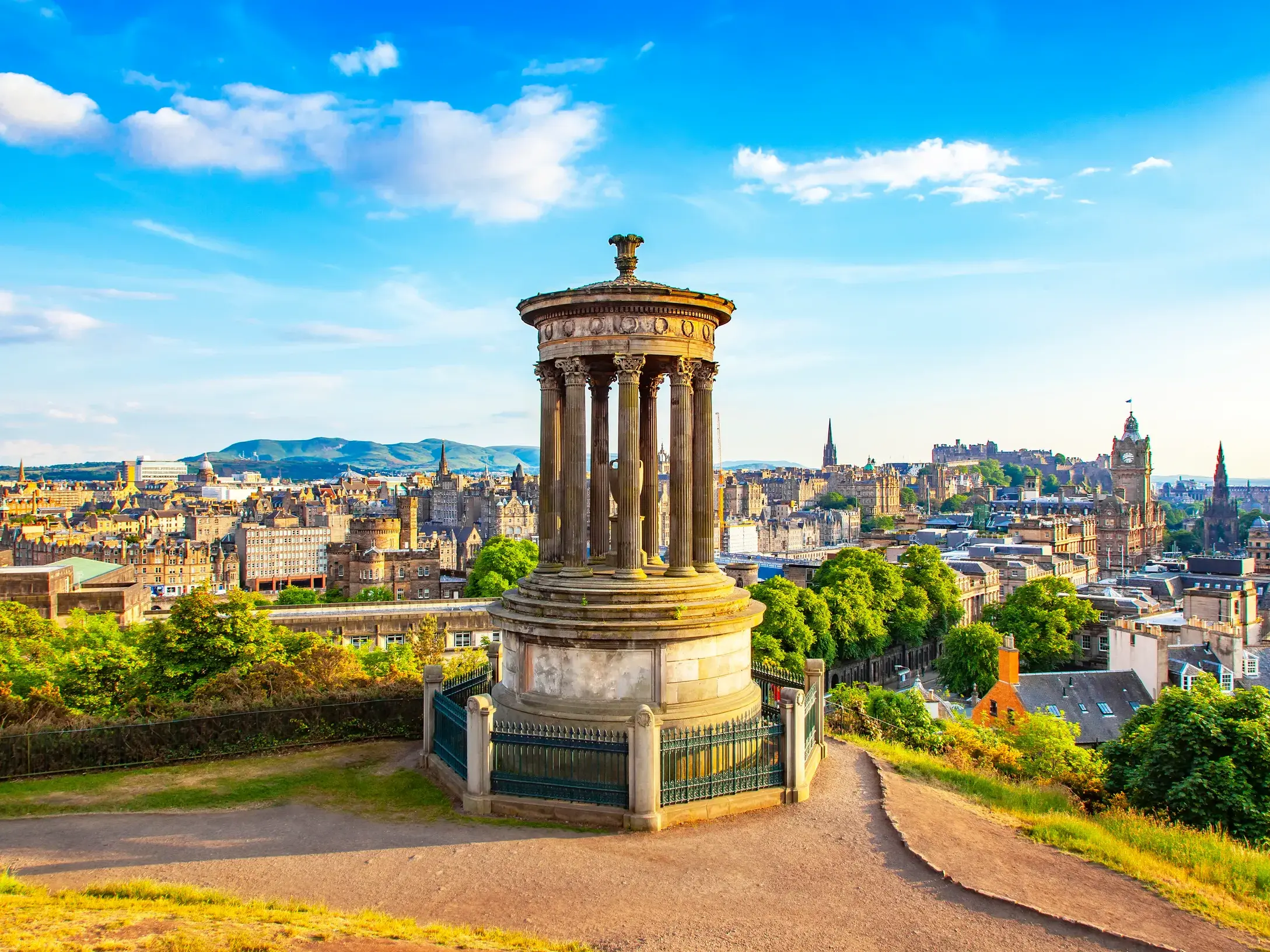 Ikonischer Blick vom Calton Hill auf Edinburghs Skyline mit dem Dugald Stewart Monument und dem Castle am Horizont.