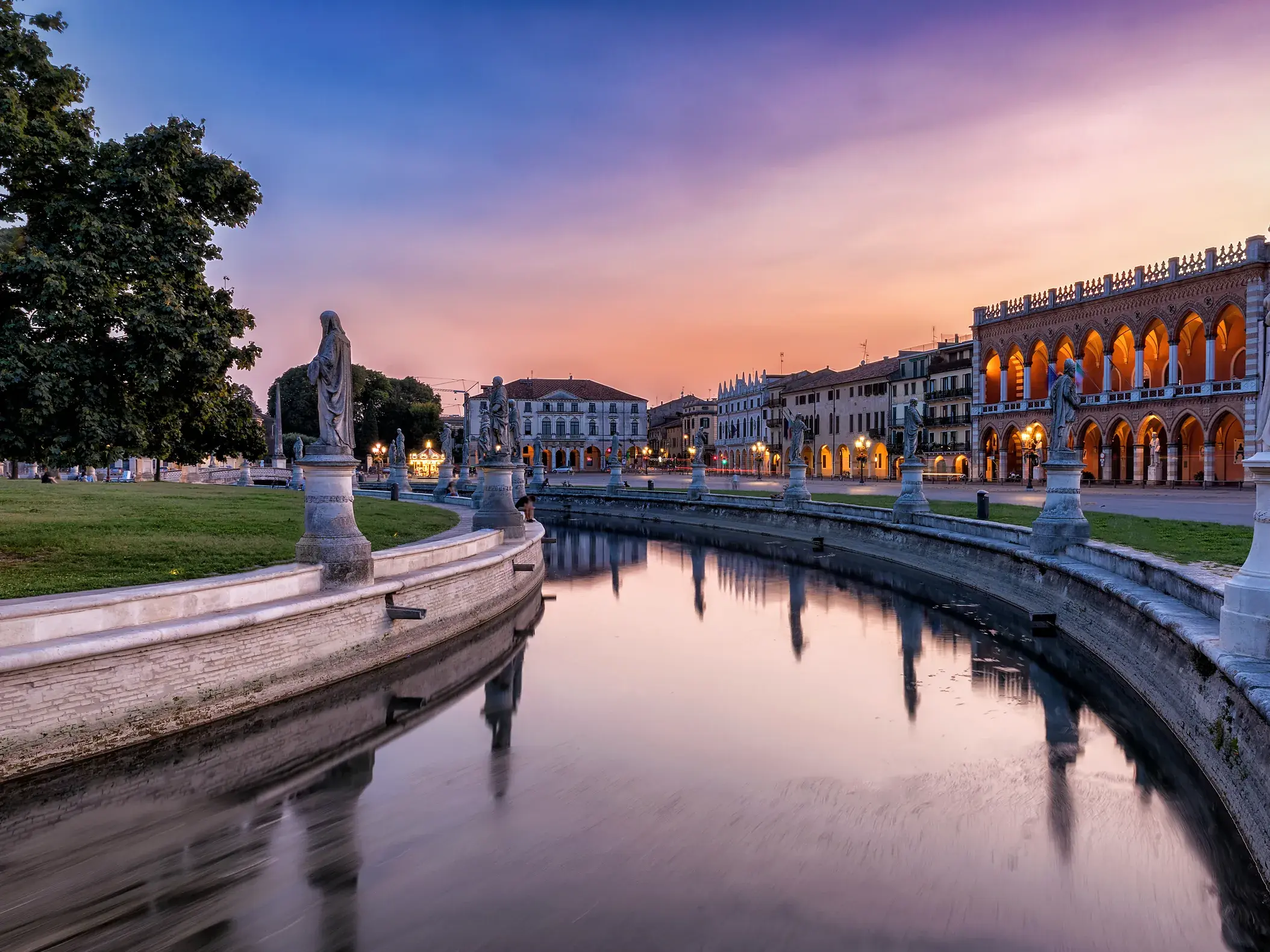 Der von Statuen gesäumte Kanal des Prato della Valle in Padua bei einem stimmungsvollen Sonnenuntergang in Venetien.
