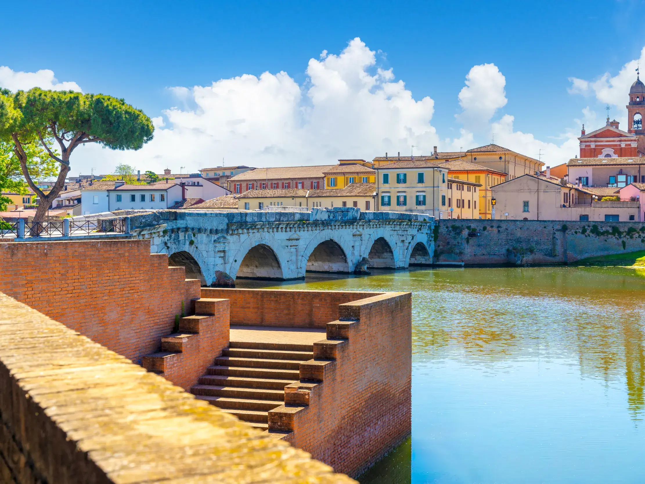Malerischer Blick über den Fluss auf die altrömische Brücke und die historische Altstadt von Rimini in der Emilia-Romagna.