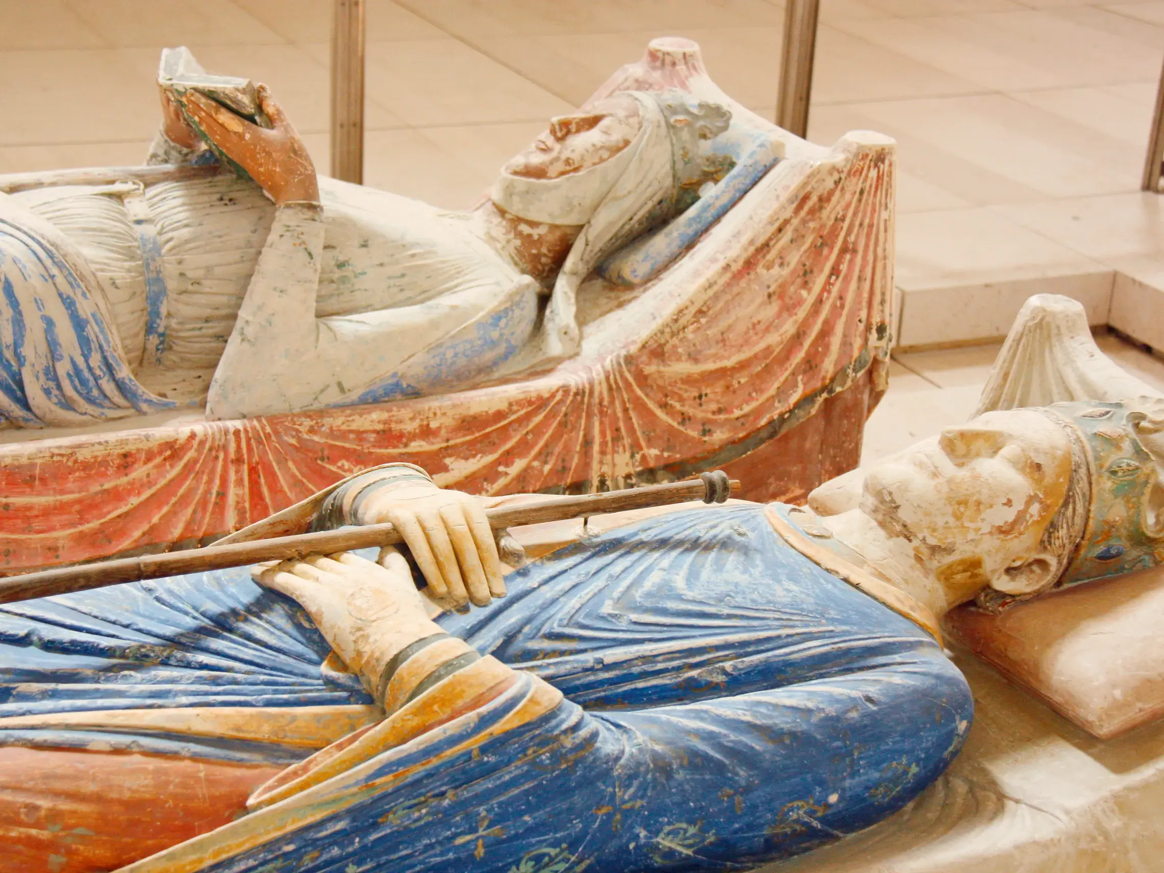 Nahaufnahme der bunt bemalten, liegenden Grabfiguren von Eleonore von Aquitanien und Heinrich II. in der Abteikirche Fontevraud.