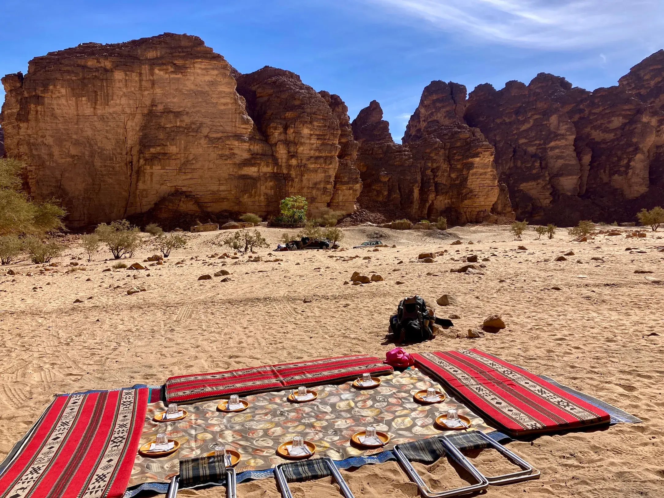 Gedeckter Rastplatz für ein Picknick im Sand der Sahara mit Blick auf die beeindruckenden Felsen im Tassili n'Ajjer.