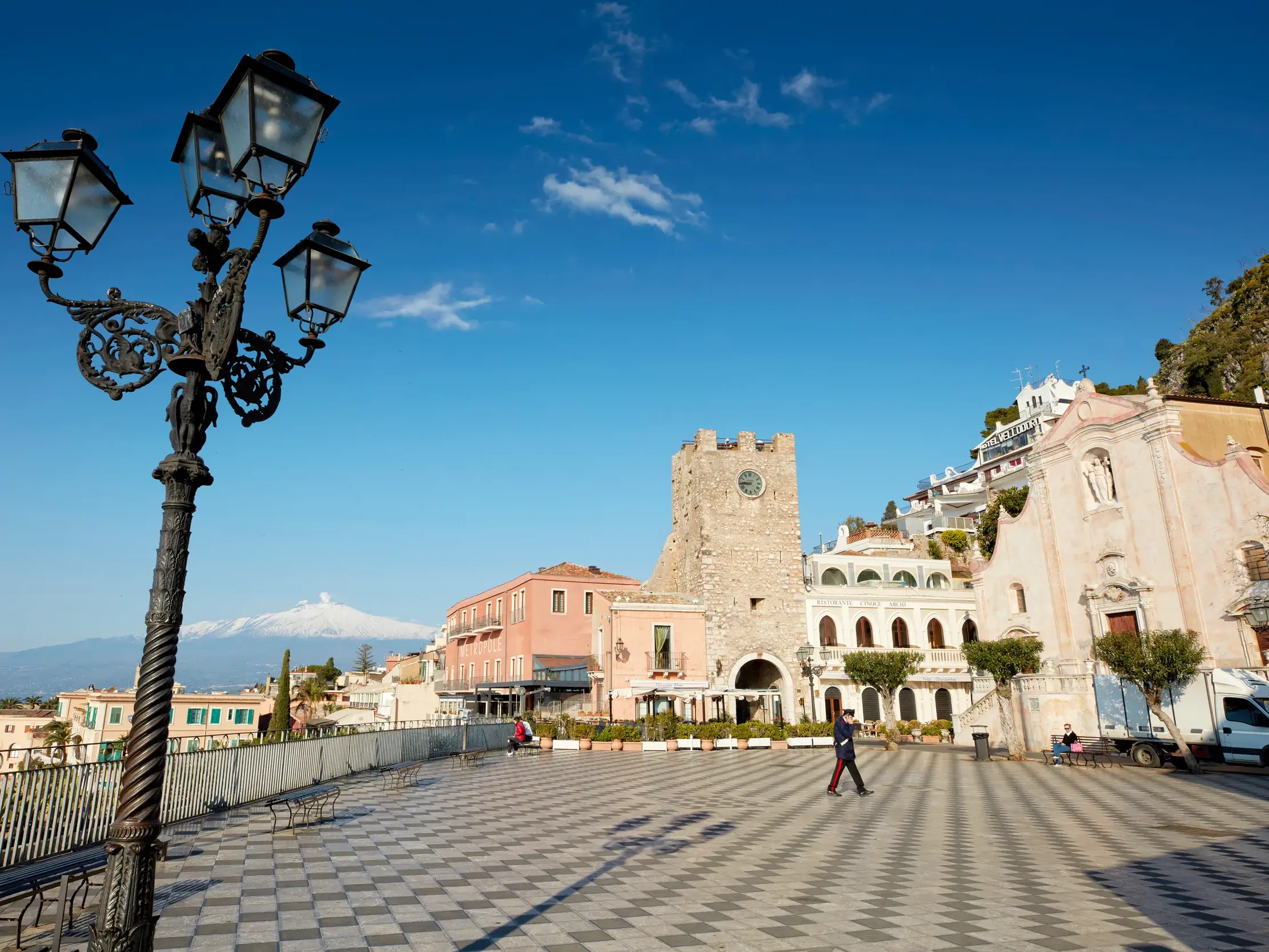 Historische Laterne auf der Piazza IX Aprile in Taormina, im Hintergrund die Kirche San Giuseppe und der Vulkan Ätna.