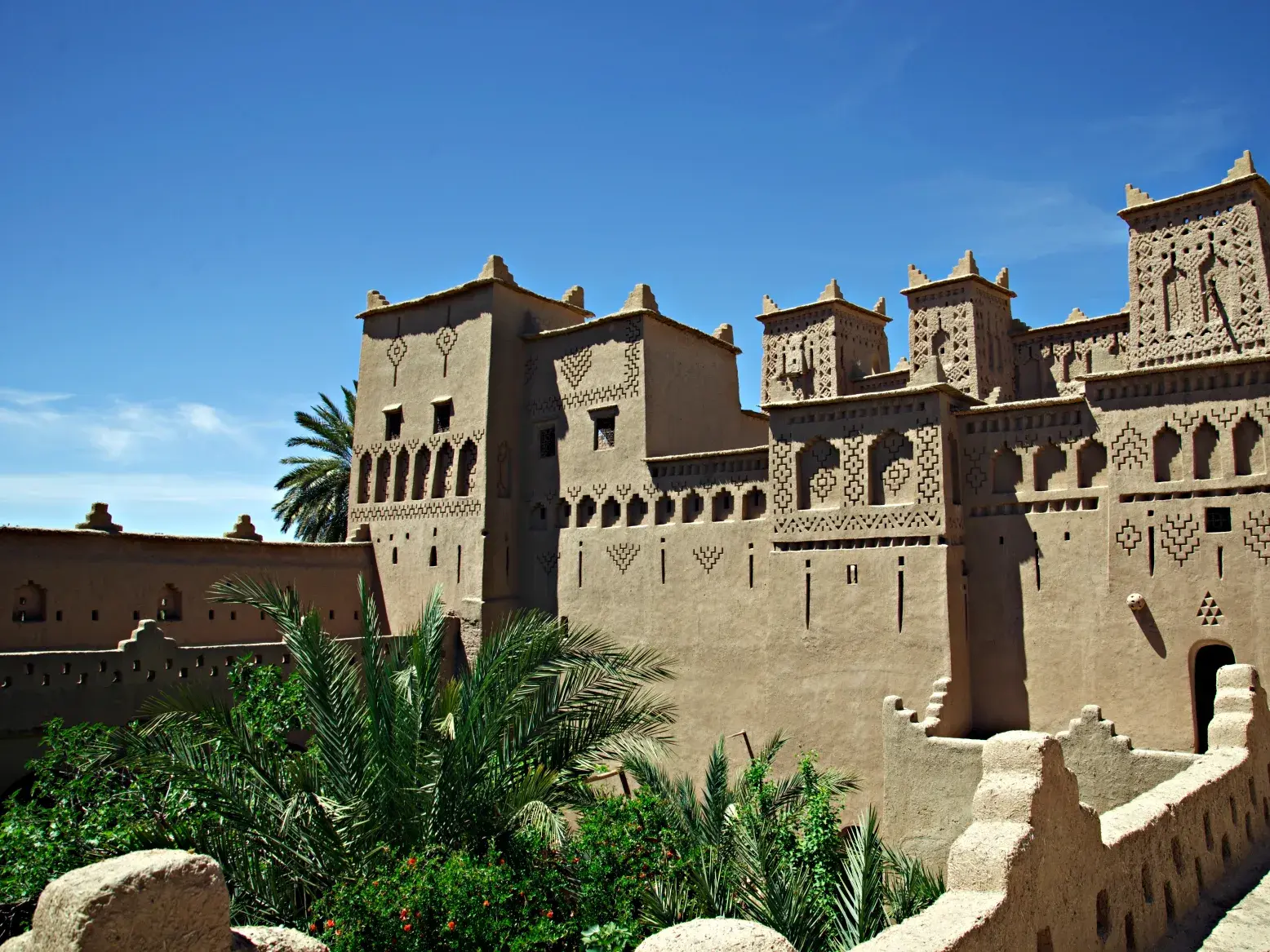 Imposante Lehmburg Kasbah Amerhidil bei Skoura mit Palmen an der Straße der Tausend Kasbahs während einer Wanderreise in Marokko.