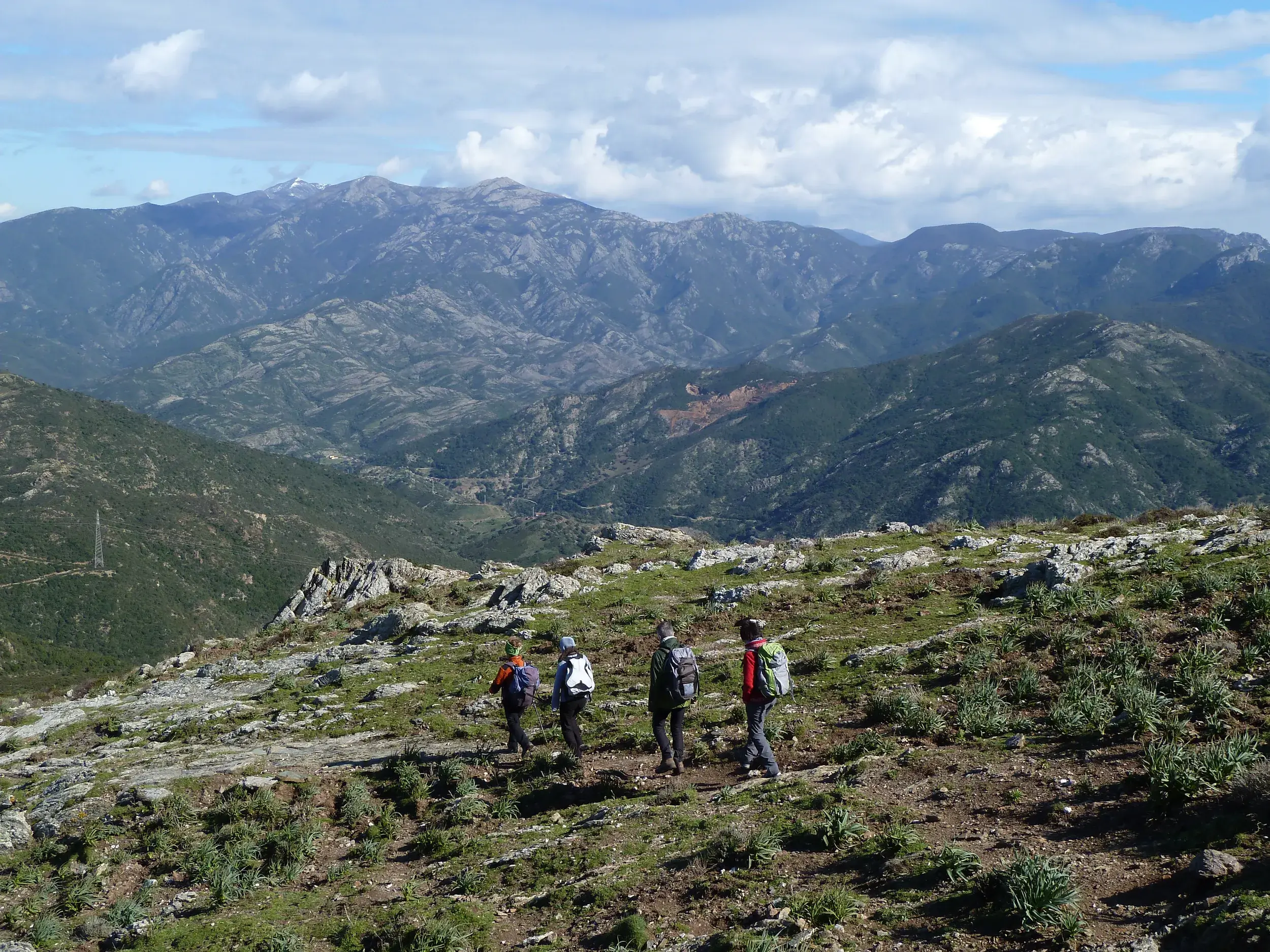 Kleine Wandergruppe auf einem steinigen Bergpfad mit weitem Panoramablick auf die Punta La Marmora im Gennargentu-Gebirge.