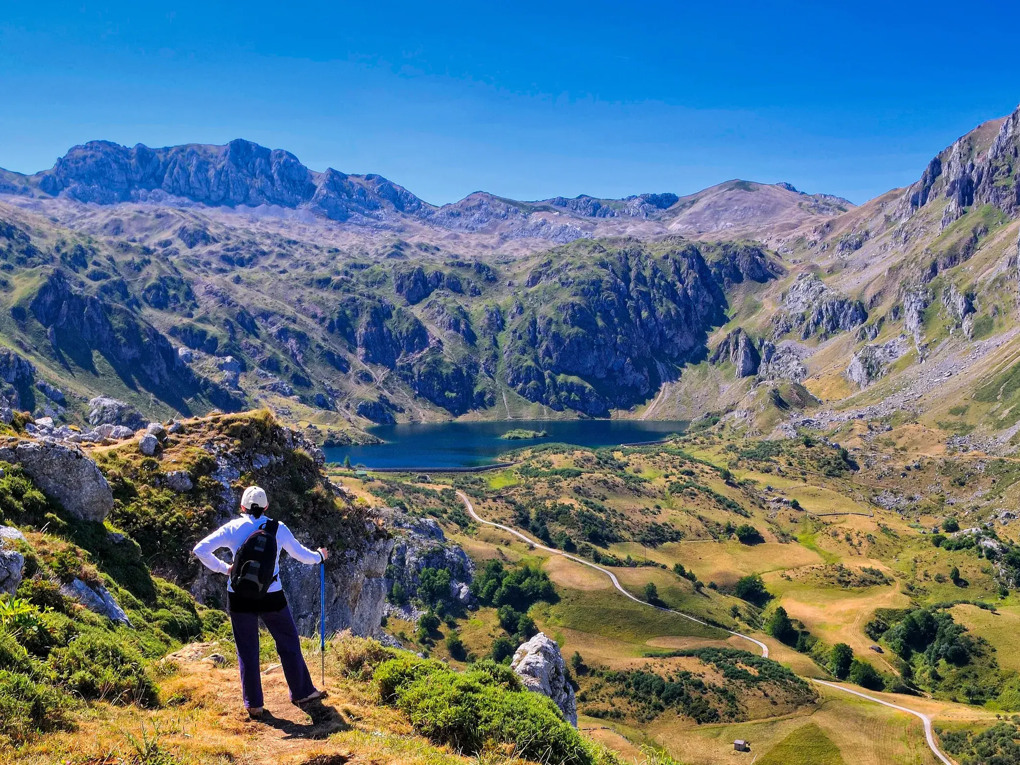 Eine Wanderin mit Rucksack blickt bei einer Trekking-Tour auf die malerischen Saliencia-Seen im Naturpark Somiedo.