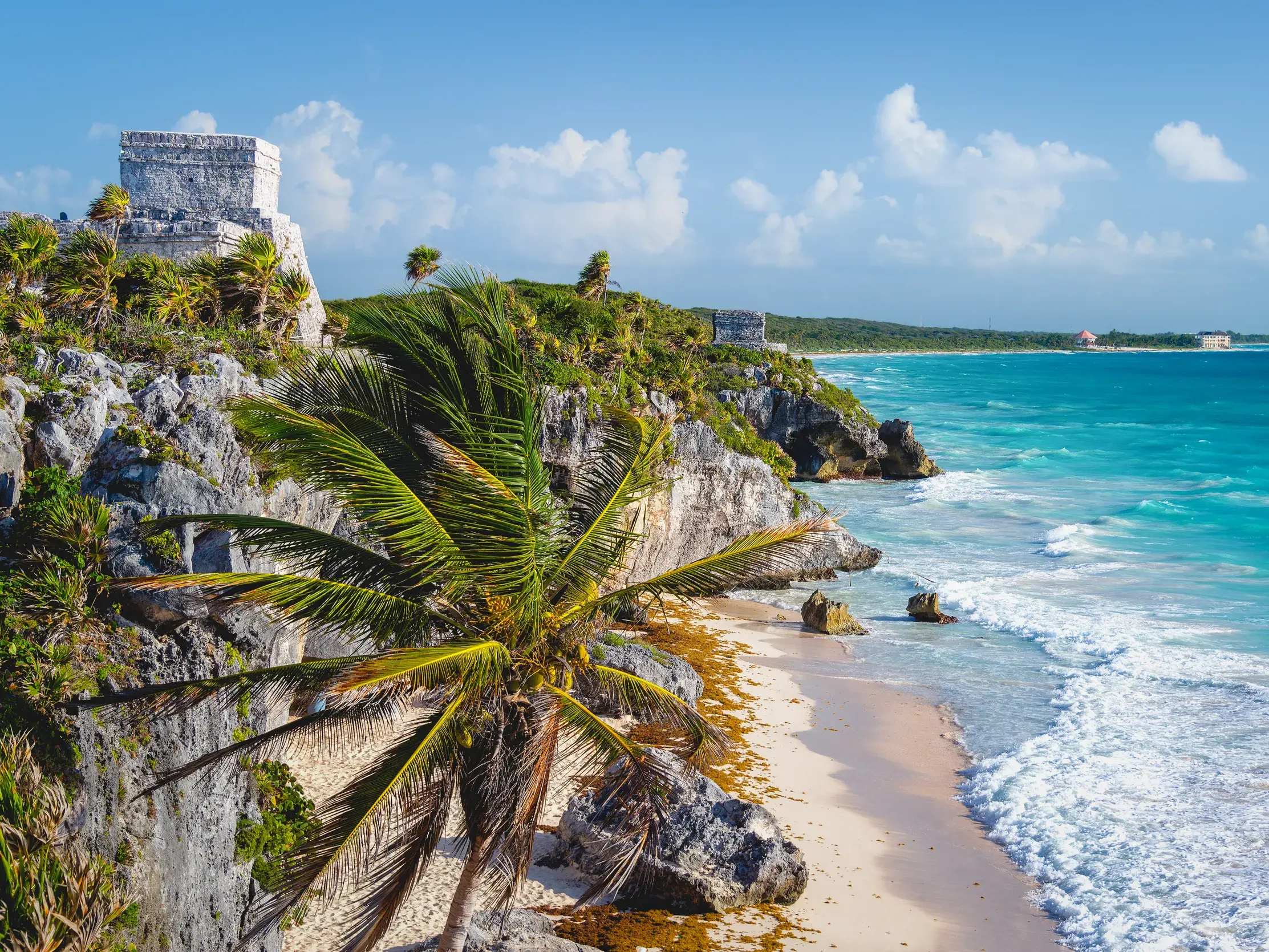 Die antiken Maya-Ruinen von Tulum thronen auf einer Felsklippe über dem türkisfarbenen Meer der Karibik an einem sonnigen Tag.