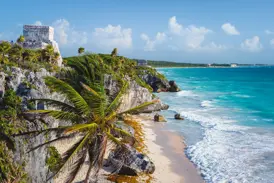 Die antiken Maya-Ruinen von Tulum thronen auf einer Felsklippe über dem türkisfarbenen Meer der Karibik an einem sonnigen Tag.