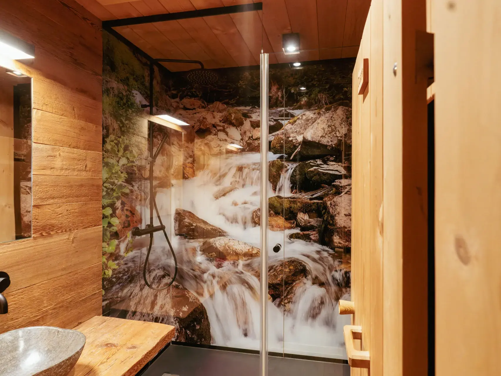 Modern-rustikales Bad im Wurzerhof im Villgratental mit Holzelementen und begehbarer Dusche mit Wasserfallmotiv.