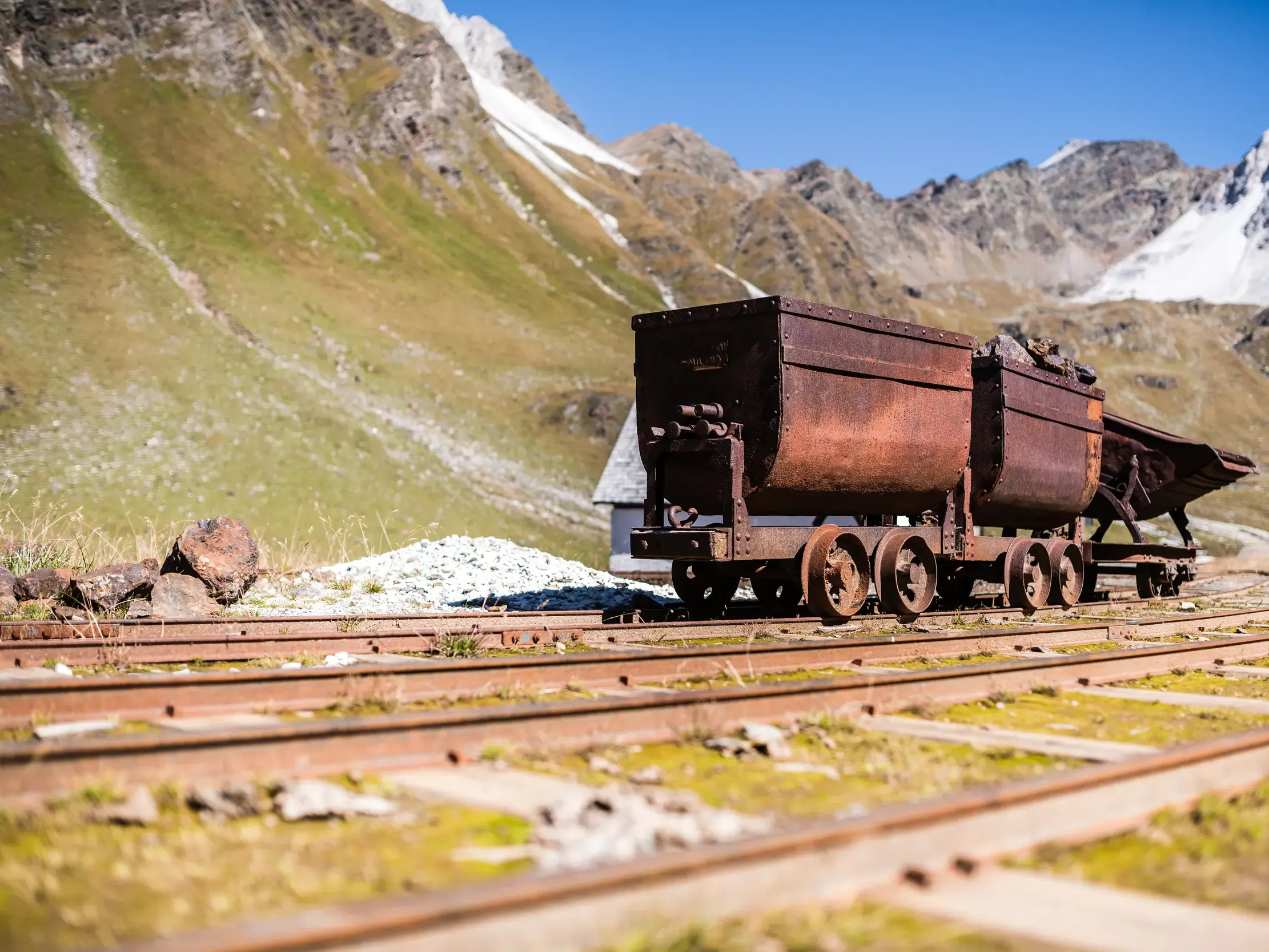 Historische, rostige Erzwagen der Grubenbahn auf dem Lehrpfad am Schneeberg in den Stubaier Alpen bei Sonnenschein.
