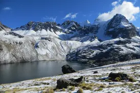 Imposante, schneebedeckte Gipfel der Königskordillere in Bolivien ragen über der dunklen Laguna Chiar Khota auf.